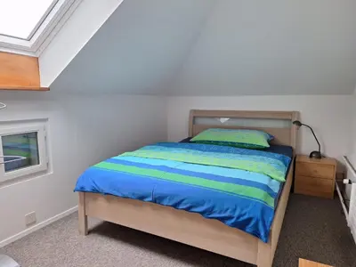 a bedroom with a bed with a blue and green comforter at Dachwohnung in Niederuzwil
