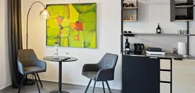 a table with two chairs and a painting of a woman at RS Boardinghouse Self Check-In Free Parking in St. Gallen