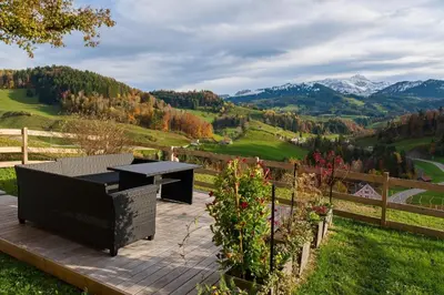 a picnic table on a deck with a view of mountains at BnB Sonder in Urnäsch