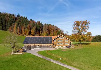 a house with solar panels on the side of a field at BnB Sonder in Urnäsch