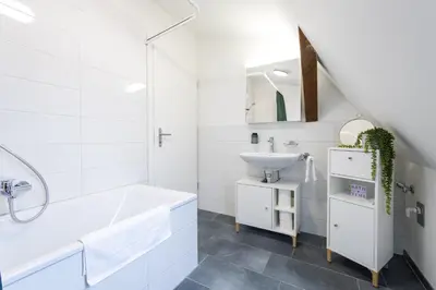 a white bathroom with a sink and a bath tub at Duplex Apartment - Lake Constance - Self Check-in - Parking - 4-Keys Apartments in Rorschach