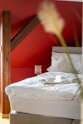 a white bed in a room with a red wall at Duplex Apartment - Lake Constance - Self Check-in - Parking - 4-Keys Apartments in Rorschach