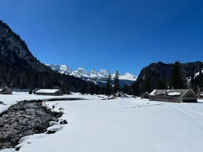 a field covered in snow with houses and mountains at Apartment Chäserruggblick by Interhome in Unterwasser