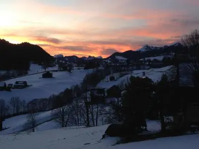 a sunset on a snowy hill with a village in the snow at Holiday Home Neuer Sigerst by Interhome in Wildhaus