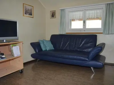 a blue leather couch in a living room with a television at Apartment Sutter in Brülisau bei Appenzell by Interhome in Brülisau