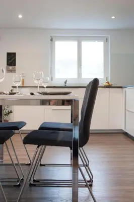 a kitchen with a table and chairs and two windows at Apartment Ferien im Toggenburg by Interhome in Krummenau