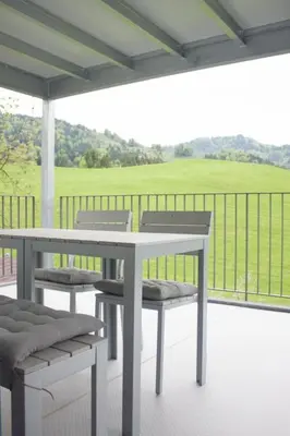 a table and chairs on a porch with a view of a field at Apartment Ferien im Toggenburg by Interhome in Krummenau