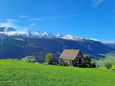 a house on a hill with mountains in the background at Apartment by Interhome in Unterwasser