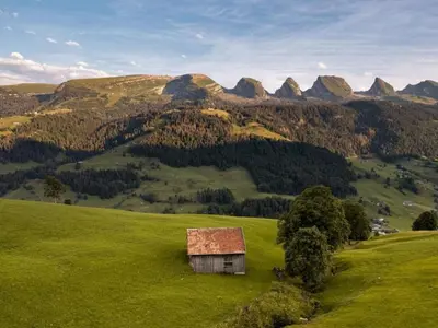an old house on a green hill with mountains in the background at Apartment by Interhome in Unterwasser