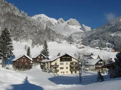 a snow covered mountain with houses in the foreground at Apartment Weiherhof by Interhome in Wildhaus