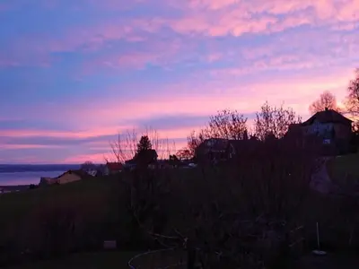 a sunset over a field with a house and the water at Holiday Home Ferien in der Vogelherd by Interhome in Wolfhalden
