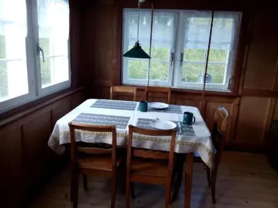 a dining room with a table with chairs and windows at Holiday Home Ferien in der Vogelherd by Interhome in Wolfhalden