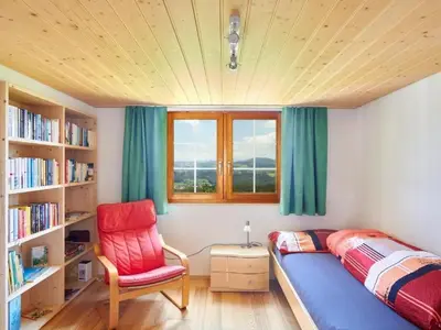 a bedroom with a bed and a chair and bookshelves at Apartment Hof Höchi by Interhome in Bruggen