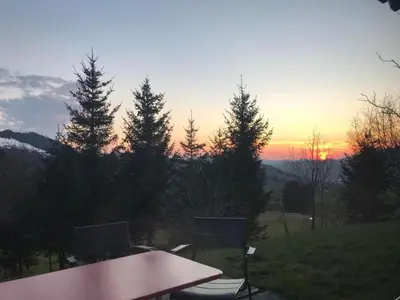 a table and chairs with the sunset in the background at Holiday Home Soldanella by Interhome in Appenzell