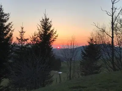 a sunset over a hill with trees in the foreground at Holiday Home Soldanella by Interhome in Appenzell