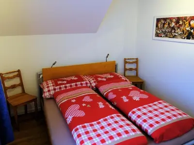 a bed with two red and white pillows on it at Apartment Rätia by Interhome in Wolfhalden