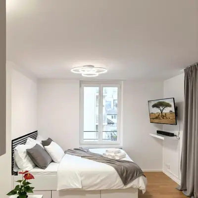 a white bedroom with a bed and a window at McNeal Solutions Zentrale Lage direkt am Roten Platz in St. Gallen