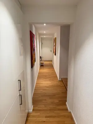 a hallway with white walls and wood floors and paintings at McNeal Solutions Zentrale Lage direkt am Roten Platz in St. Gallen