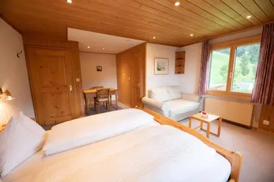 a bedroom with a bed and a chair and a table at Sonnmatt Bergpension & Gesundheitszentrum in Ebnat