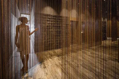 a woman standing behind a curtain in a room at Säntis - das Hotel in Schwagalp
