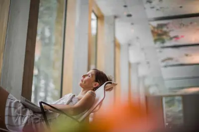 a woman sitting in a chair looking out a window at Säntis - das Hotel in Schwagalp
