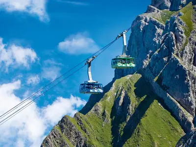 two gondolas in front of a mountain at Säntis - das Hotel in Schwagalp