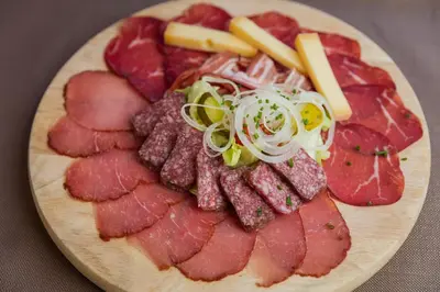a plate of cured meats and cheese on a table at Säntis - das Hotel in Schwagalp