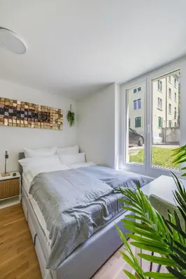a white bedroom with a large bed and a window at Urban Hideaway Studio St Gallen Center in St. Gallen