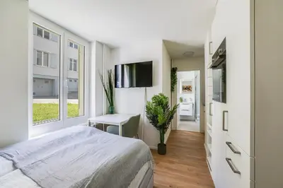 a bedroom with a bed and a desk and a tv at Urban Hideaway Studio St Gallen Center in St. Gallen