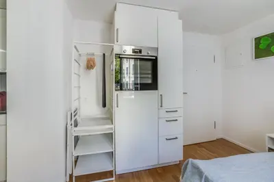 a white refrigerator in a white kitchen with a ladder at Urban Hideaway Studio St Gallen Center in St. Gallen
