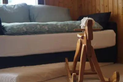 a wooden rocking chair in front of a bed at Naturnah und familienfreundlich in Degersheim