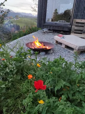 a fire pit in a garden with flowers and a bench at Ihre Wohlfühloase in Schwellbrunn