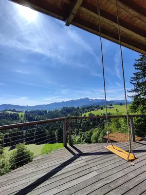 a porch swing with a view of the mountains at Ihre Wohlfühloase in Schwellbrunn