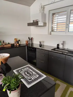 a kitchen with black cabinets and a sink and a table at Ihre Wohlfühloase in Schwellbrunn