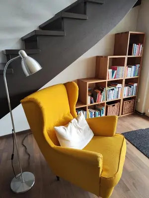 a living room with a yellow chair and a lamp at Ihre Wohlfühloase in Schwellbrunn