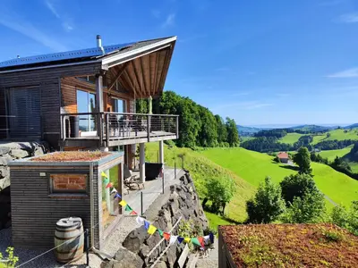 a house on the side of a hill with flags at Ihre Wohlfühloase in Schwellbrunn