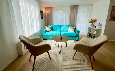 a living room with a blue couch and two chairs at Sunset I Bodensee I St Gallen I Bregenz I Appenzell I Vaduz in Rorschacherberg