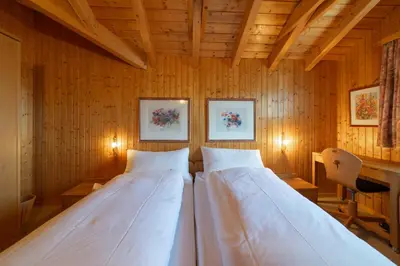 a bedroom with two beds in a wooden wall at Sonnegge in Wildhaus