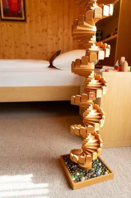a tower of books on a wooden stand next to a bed at Sonnegge in Wildhaus