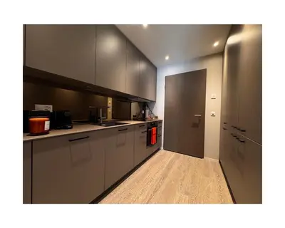 a kitchen with white cabinets and a door to a hallway at Zuhause am Bodensee in Bottighofen