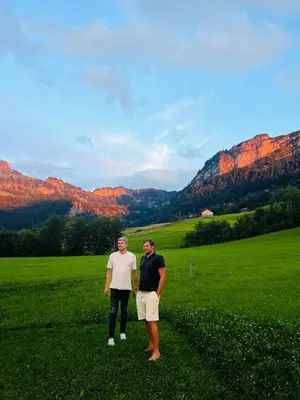 two men standing in a field with mountains in the background at 4 bedroom house for 8 guests in Brülisau