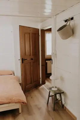 a bedroom with a bed and a door and a stool at 4 bedroom house for 8 guests in Brülisau
