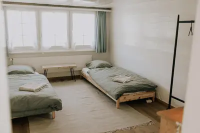 two beds in a room with two windows at 4 bedroom house for 8 guests in Brülisau