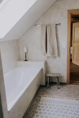 a white bedroom with a bed and a stool at Quiet exclusive house for 6 people in Brülisau