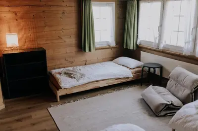 a bedroom with a bed and a couch and windows at Zimmer Fählensee im Appenzeller Ferienhaus in Brülisau