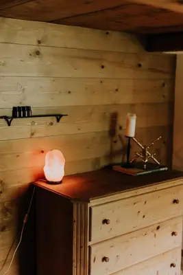 a room with a wooden wall with a lamp and a candle at Zimmer Fählensee im Appenzeller Ferienhaus in Brülisau
