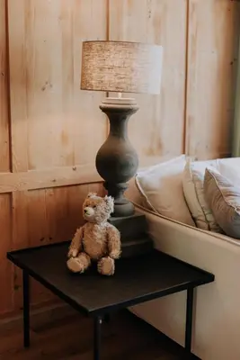 a teddy bear sitting on a table next to a bed at Zimmer Alpstein im Appenzeller Ferienhaus in Brülisau