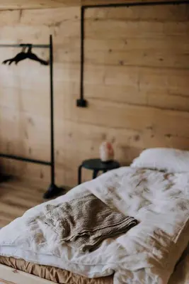 a bed in a room with a wooden wall at Zimmer Alpstein im Appenzeller Ferienhaus in Brülisau
