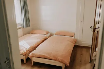 two beds in a small room with a window at Zimmer Appenzell im Appenzeller Ferienhaus in Brülisau