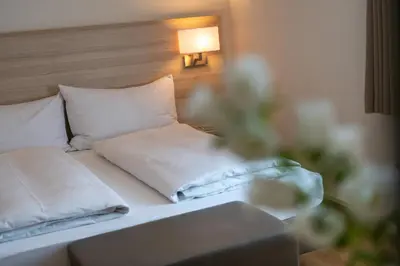 a bedroom with a bed with white sheets and pillows at Hotel Garni Rössli in St. Gallen